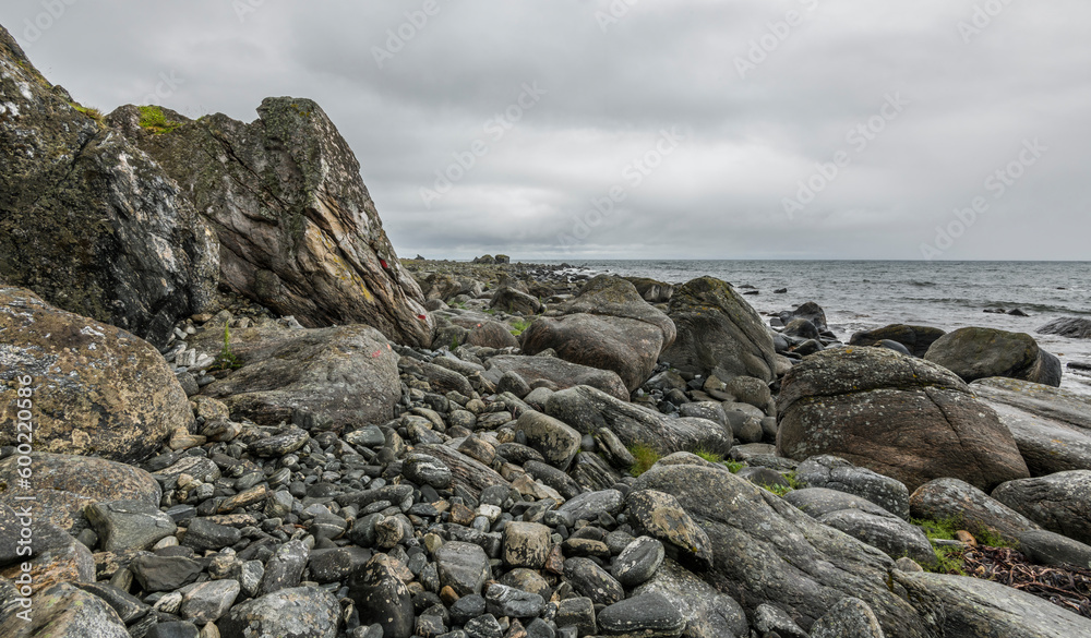 View on a rocky beach on Vaeroy island ( Værøy ) on Lofoten archipelago with a moody stormy sky. Boulders, rocks, Norway, wilderness. Bad weather. day, summer. copy space, negative space