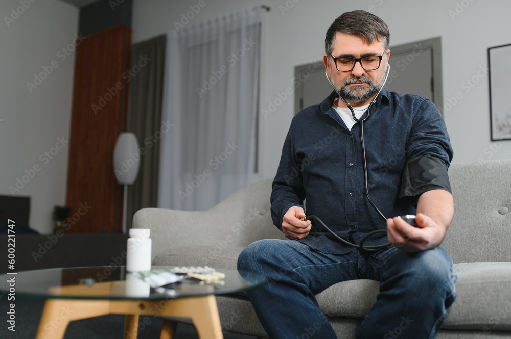 Senior caucasian retired male taking blood pressure at home Senior caucasian retired male taking blood pressure at home