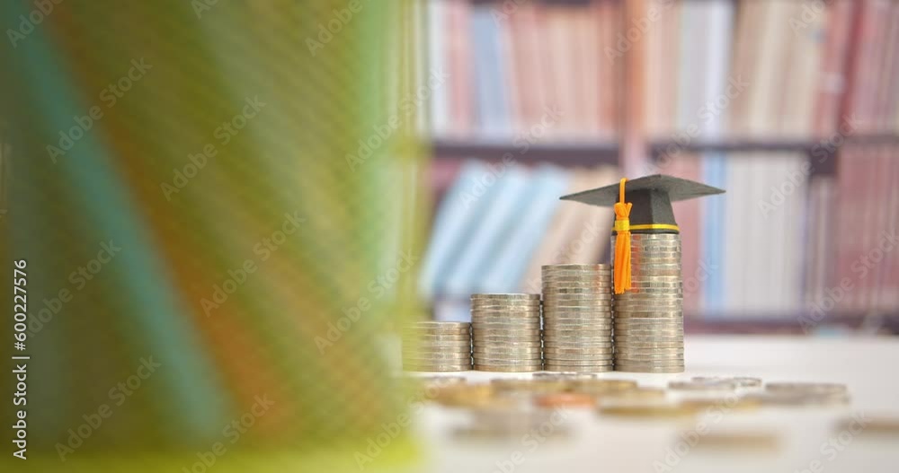 Tuition payment or tuition fee, expense for graduate study abroad program concept : Black graduation cap on stacks of coins, depicting fees charged by education institution for instruction or services