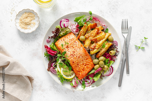 Salmon fillet grilled, fried potato and fresh vegetable green salad, top view
