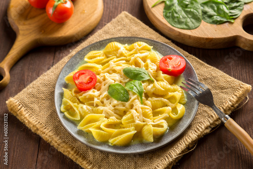 Pasta in a creamy sauce with cheese next to the planks of tomatoes, a knife and greens on a linen napkin.