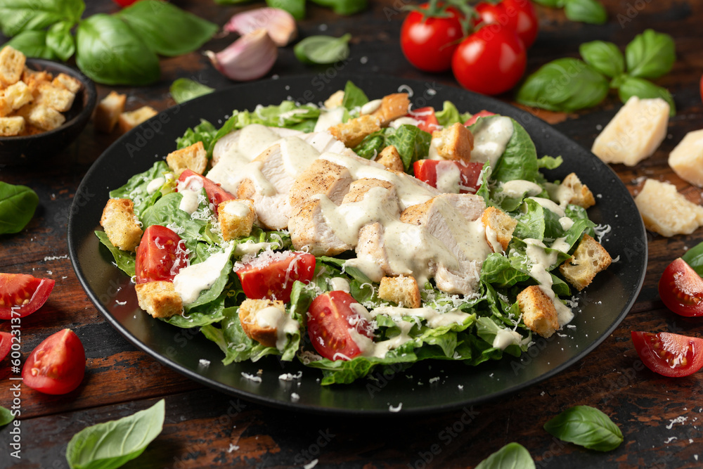 A delicious chicken caesar salad with parmesan cheese, tomatoes, croutons and dressing - obrazy, fototapety, plakaty 