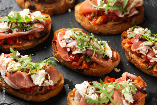 Konstfotografi Parma ham and tomato bruschetta served on black slate with mozzarella, wild rock