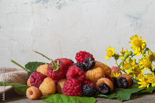 fresh rustic raspberries on a wooden table against a concrete wall.