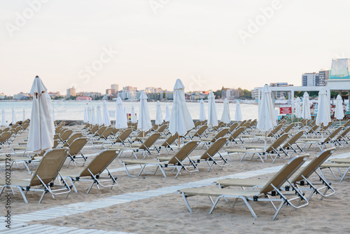 Evening beach at sunset. Empty sunbeds and umbrellas on a sandy beach near the sea © svittlana