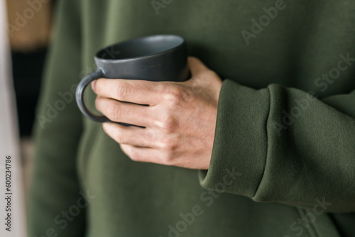 Close-up man with cup of coffee. Guy drinks coffee sitting near window