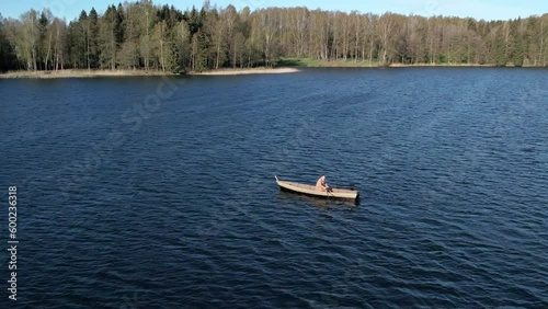 A lonely man oaring the boat at middle of lake.