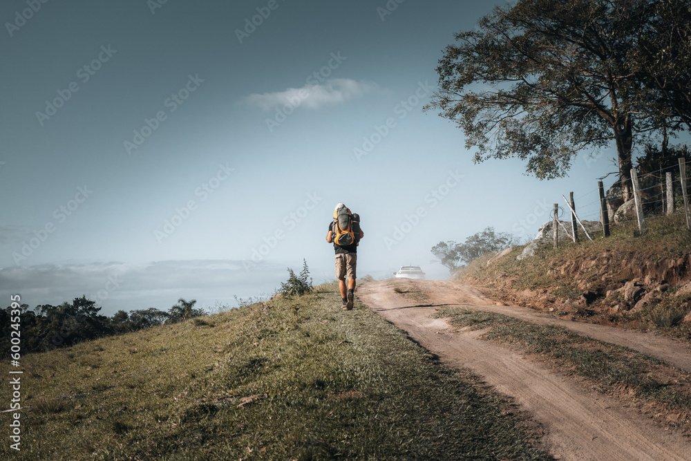 Fototapeta premium Homem mochileiro caminhando em direção ao acampamento. Espaço para texto.