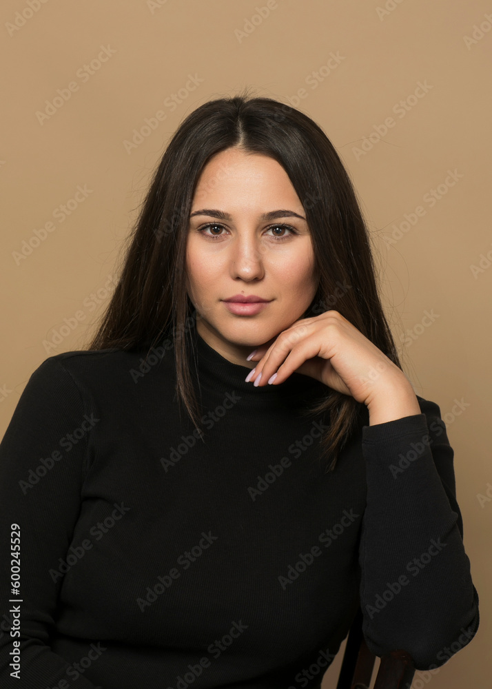 Front portrait of a sensual brunette young woman in black, isolated beige background, looking at camera. Front portrait of a sensual brunette young woman in black, isolated beige background, looking at camera.