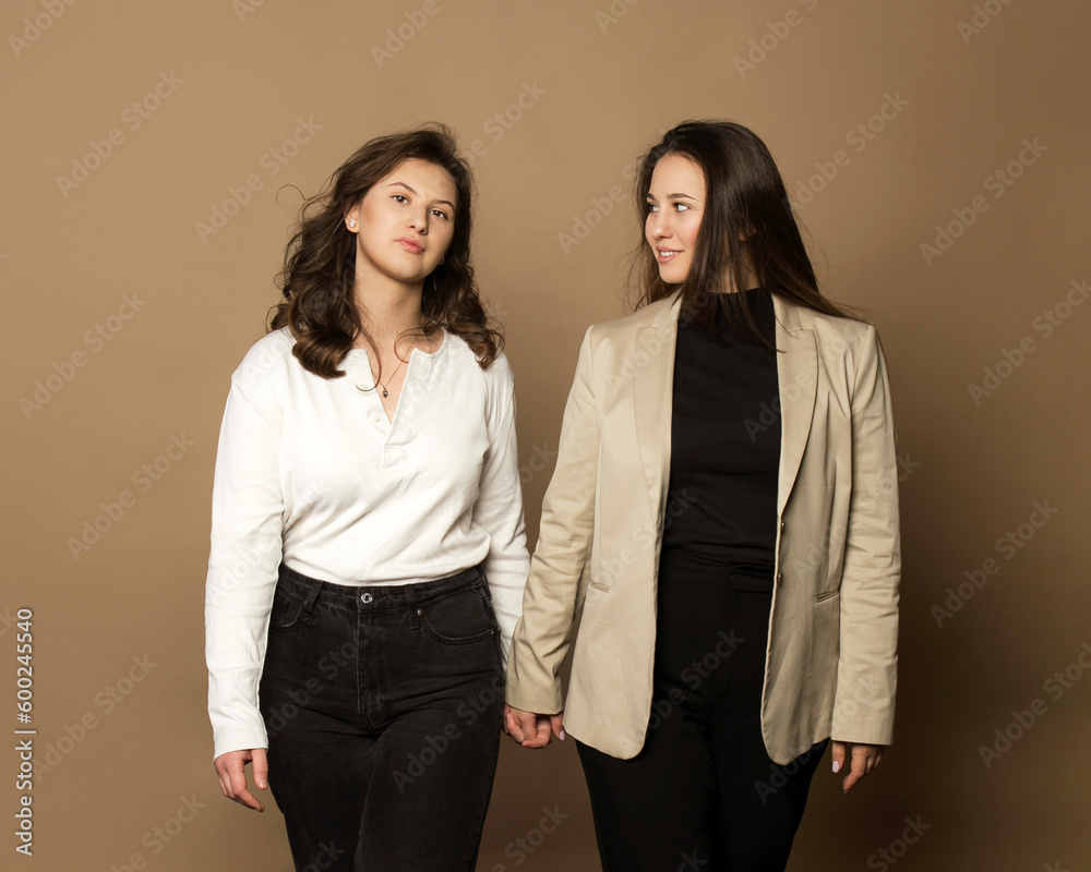 portrait of two sisters, posing in studio, beige background. portrait of two sisters, posing in studio, beige background.