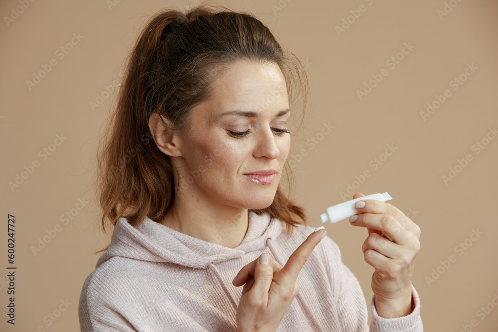 woman applying ointment using finger isolated on beige woman applying ointment using finger isolated on beige