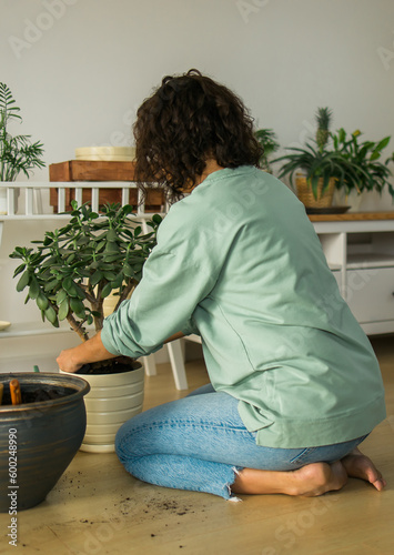 Woman grows potted plants at home watering and take care flowers - gardening and houseplant care concept