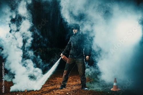 Man in a jacket testing a fire extinguisher at night