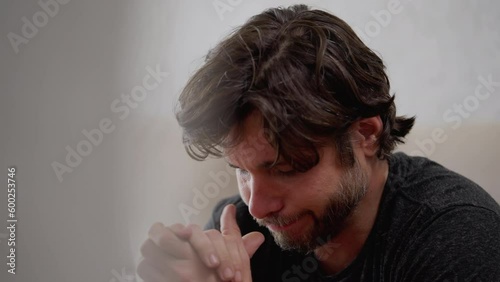 Remorseful young man in his 30s feeling overwhelmed with sadness and emotional pain while reflecting on his past