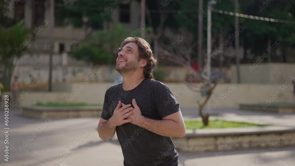 Thankful young man standing outdoors looking up at sky feeling GRATEFUL. Elated spiritual joyful person thanking God Thankful young man standing outdoors looking up at sky feeling GRATEFUL. Elated spiritual joyful person thanking God