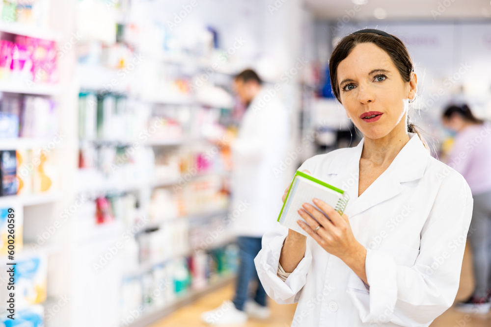 Portrait of positive female pharmacist ready to advising consumers in drug store