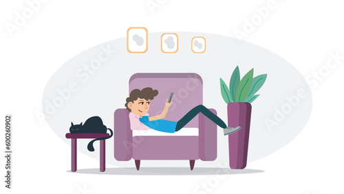 Boy is laying down on armchair and looking his telephone. Smiling boy with his telephone on armchair. Boy and his cat in living room laying down.