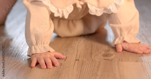 Hands of the baby child on the floor in emphasis. She reflexively moves back and forth. Natural body training before crawling and walking. photo