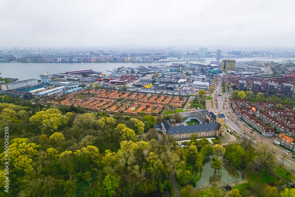 beautiful scenic drone shot of Amsterdam Center, green trees houses and a port on the river. High quality photo