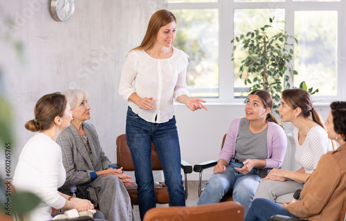 Women of different ages in casual clothes communicate on chairs in circle in office