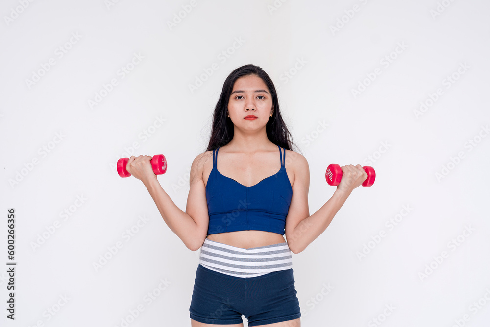 A sporty and young woman weightlifting and working out using a dumbbell. Isolated on a white background. A sporty and young woman weightlifting and working out using a dumbbell. Isolated on a white background.
