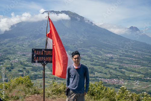 Young man Indonesian reach peak of mountain. The photo is suitable to use for adventure content media, nature poster and forest background.