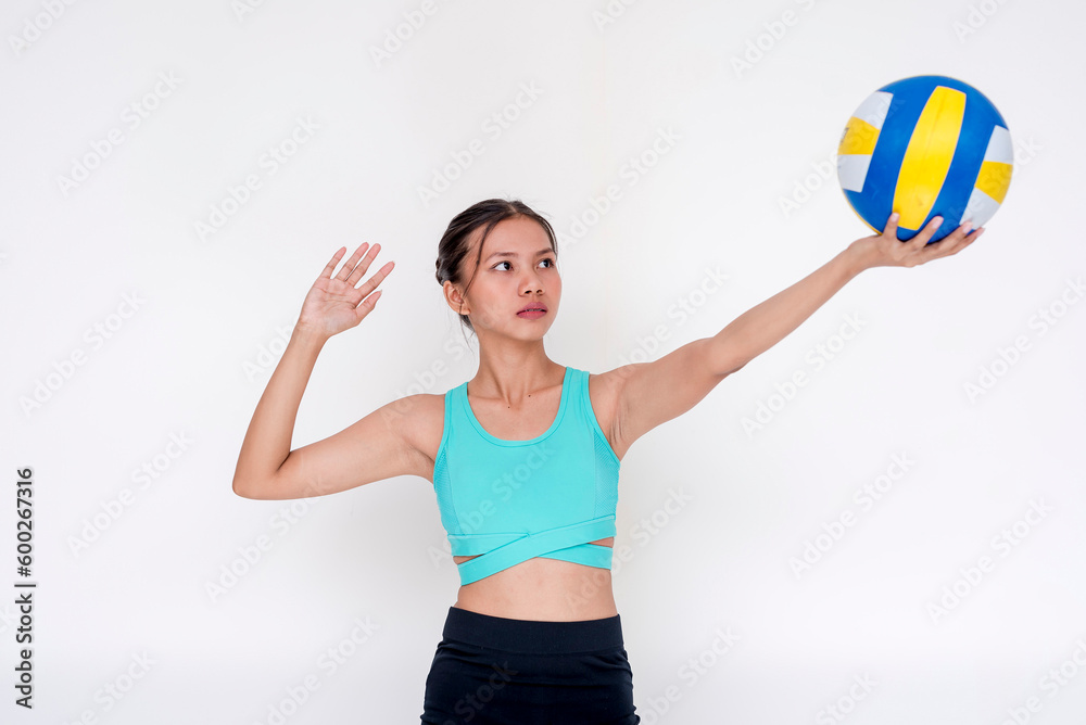 A sporty and athletic young woman doing a volleyball serve position with the ball raised on one hand. Isolated on a white background.