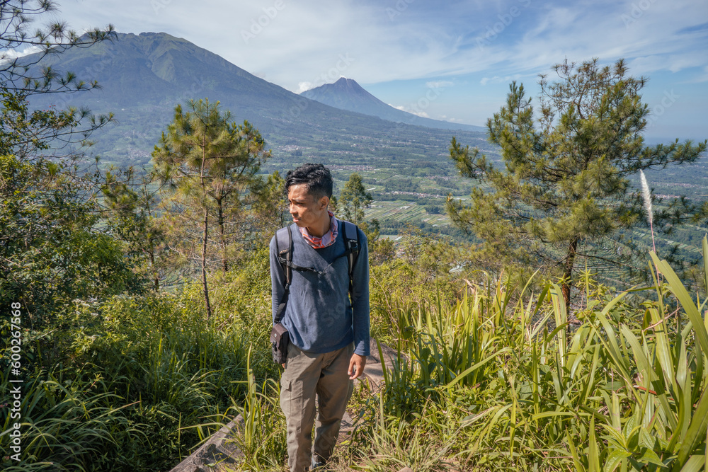 Young man Indonesian hiking mountain through the forest and foot path. The photo is suitable to use for adventure content media, nature poster and forest background. Young man Indonesian hiking mountain through the forest and foot path. The photo is suitable to use for adventure content media, nature poster and forest background.