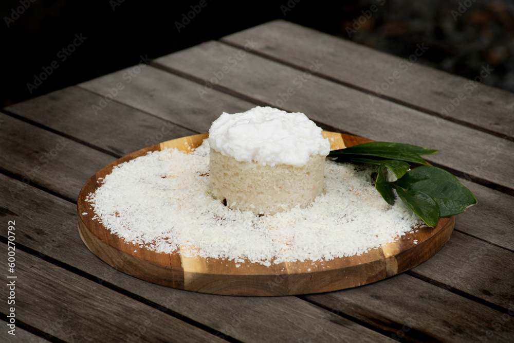 coconut cake with icing and shredded coconut on wooden board on tropical rustic table in oustide closeup coconut cake with icing and shredded coconut on wooden board on tropical rustic table in oustide closeup