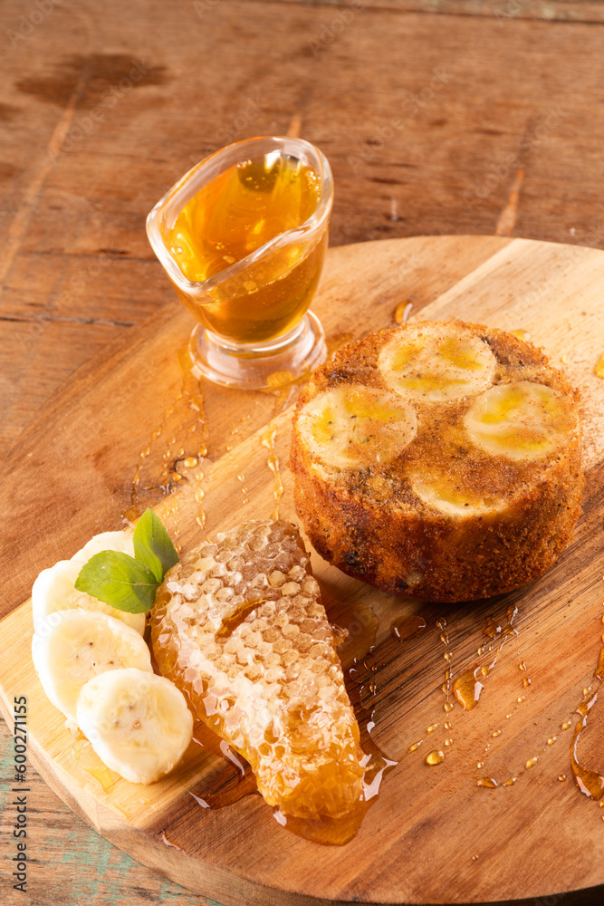 banana honey cake with wild honeycomb and banana slices on rustic wooden table portrait