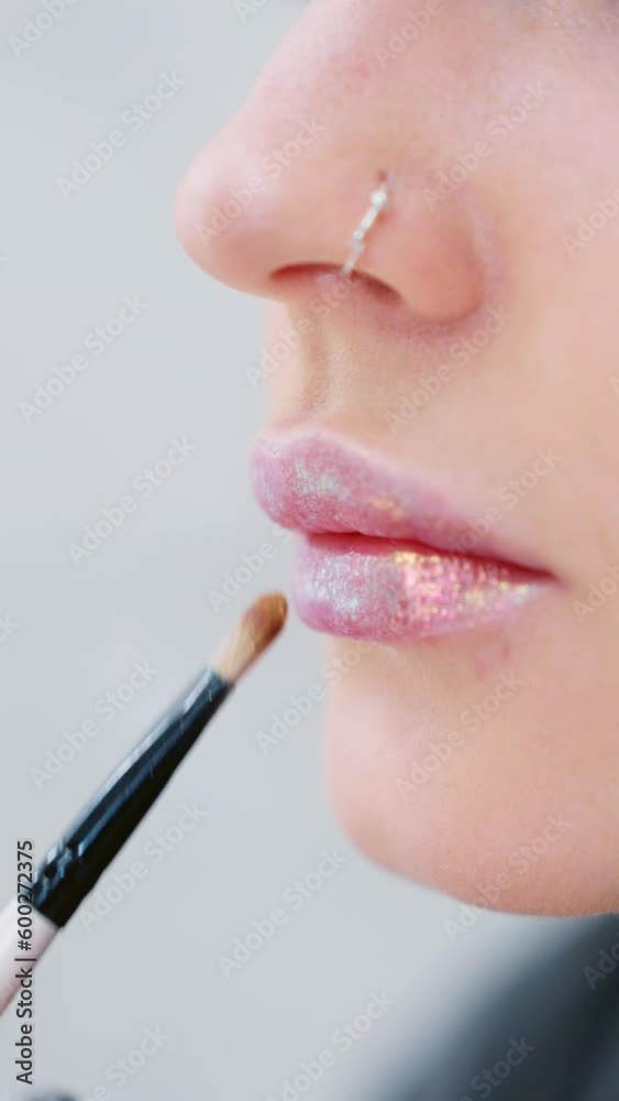 Woman applying gloss to the lips with a brush Woman applying gloss to the lips with a brush