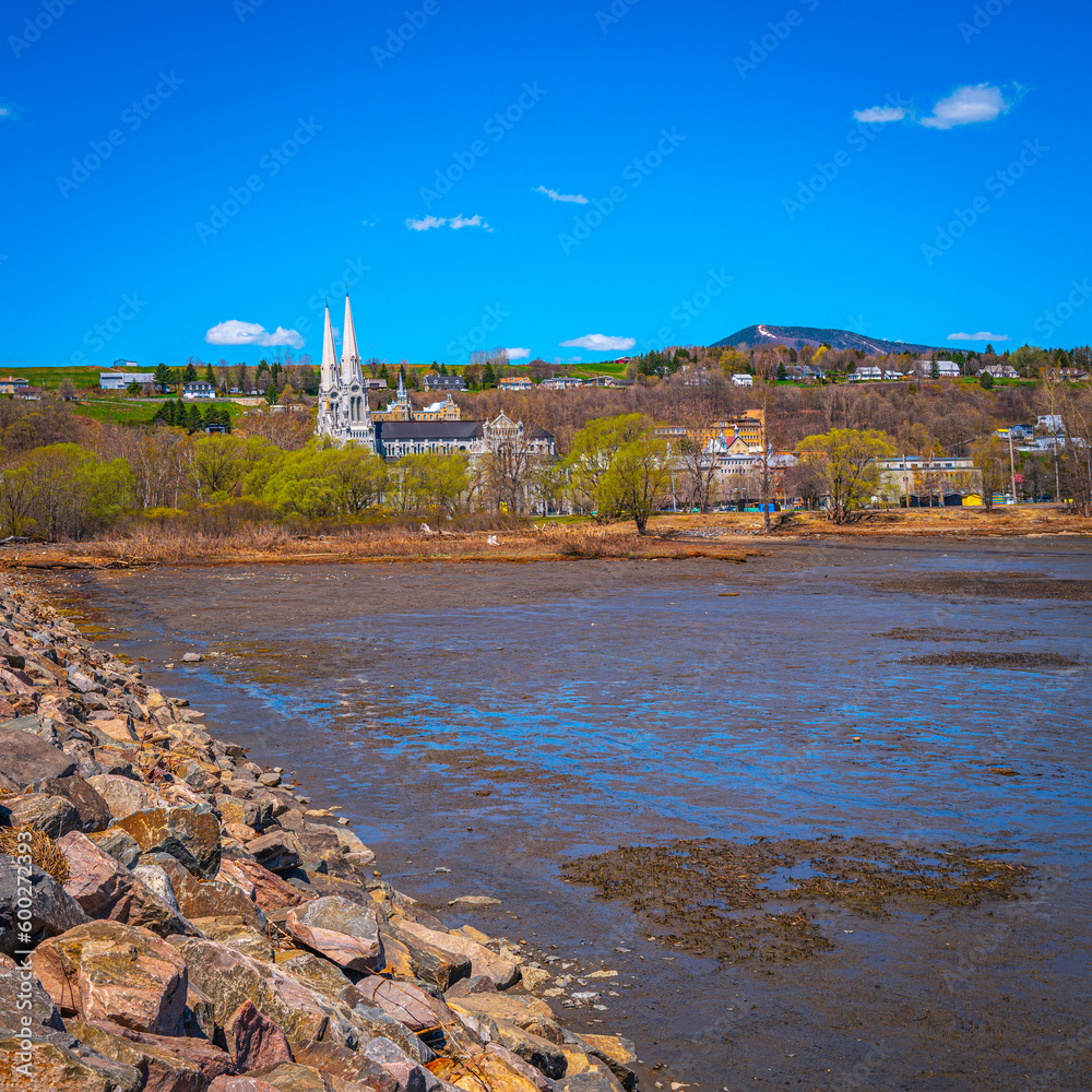 Tranquil Quebec spring landscape at Quai De La PAIX, or Peace Wharf, with the views of the Basilica of Sainte-Anne-de-Beaupre and St. Lawrence River at low tide, Canada