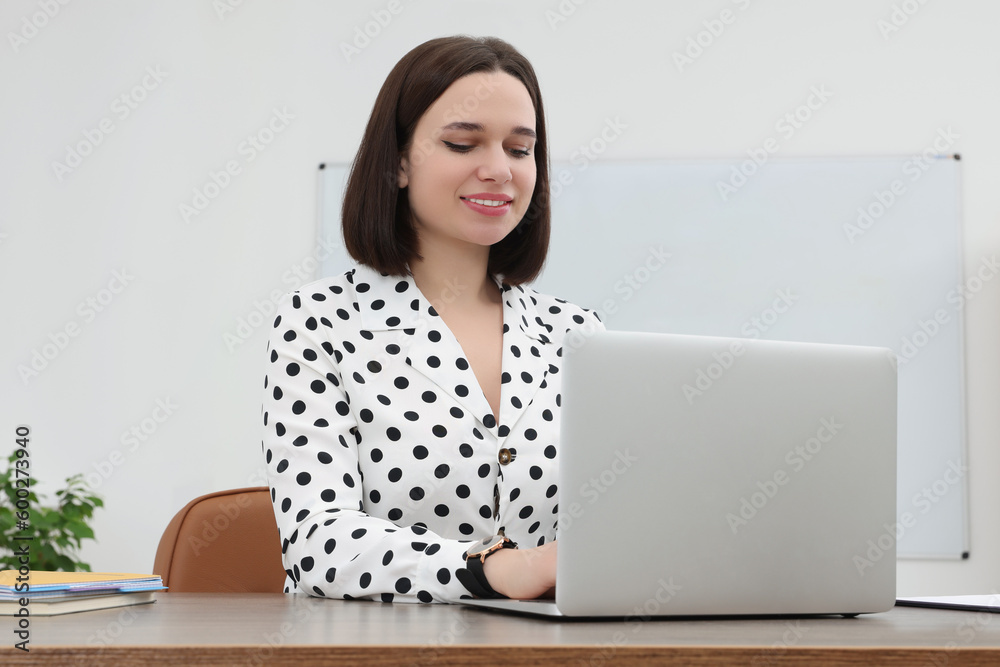 Happy young intern working with laptop at table in modern office Happy young intern working with laptop at table in modern office