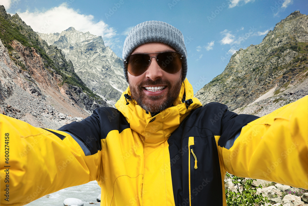 Smiling man in hat and sunglasses taking selfie in mountains Smiling man in hat and sunglasses taking selfie in mountains