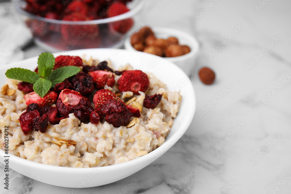 Oatmeal with freeze dried strawberries and mint on white marble table, closeup. Space for text Oatmeal with freeze dried strawberries and mint on white marble table, closeup. Space for text