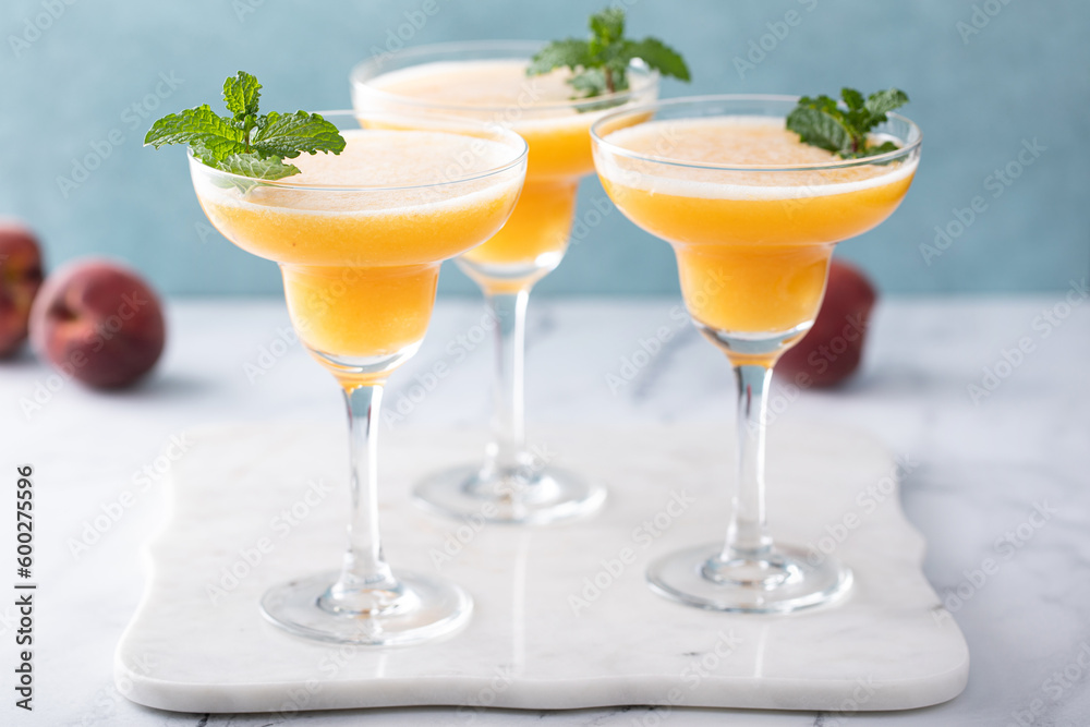 Frozen peach margaritas in three glasses with mint