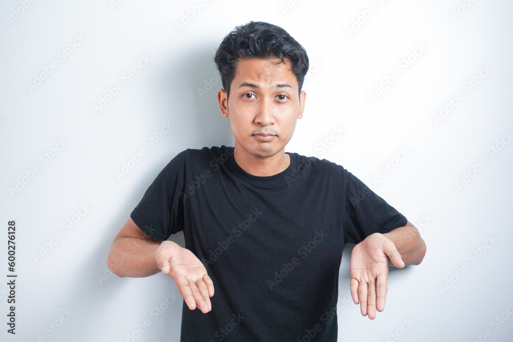 Shocked Asian man wearing black t-shirt pointing at the copy space down below him, isolated by white background Shocked Asian man wearing black t-shirt pointing at the copy space down below him, isolated by white background