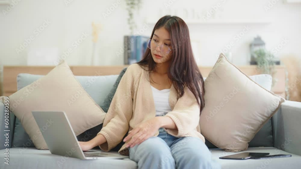 Young asian woman using computer laptop, tablet and mobile smartphone while seated on couch at home Young asian woman using computer laptop, tablet and mobile smartphone while seated on couch at home
