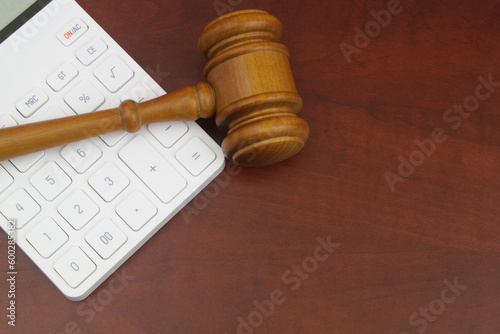 Wooden gavel and white calculator on wooden table. Arbitration concept. photo