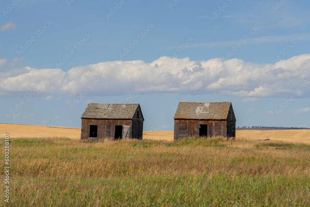 Old abandoned farm buildings in the prairie with a cloudy blue sky Old abandoned farm buildings in the prairie with a cloudy blue sky