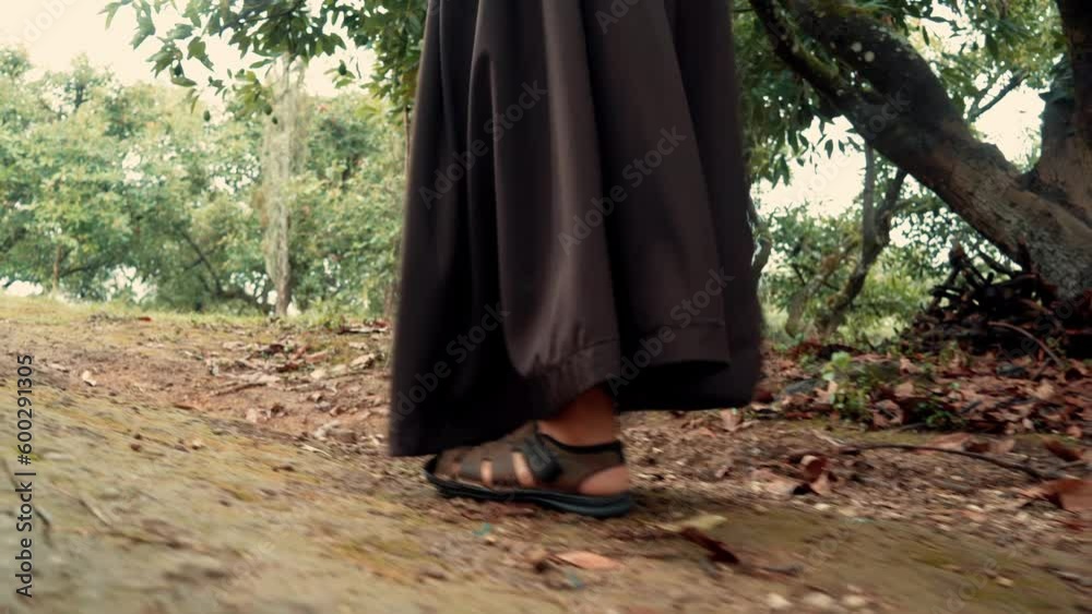 Fraile monje franciscano meditando subiendo y caminando por una montaña en un bosque al amanecer reflexionando por el camino al aire libre