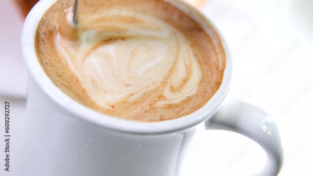 Woman hand pouring sugar and stirring coffee with spoon, coffee time. Stirring latte coffee with a spoon. High quality 4k footage. High quality 4k footage