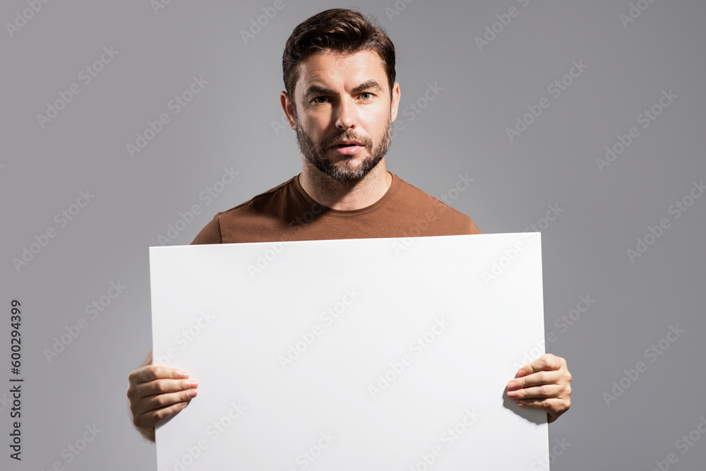 Man with empty blank banner ad on studio background. Portrait of attractive man holding empty blank poster. Man showing blank poster. Male presenting signboard, board or banner with copy space. Man with empty blank banner ad on studio background. Portrait of attractive man holding empty blank poster. Man showing blank poster. Male presenting signboard, board or banner with copy space.