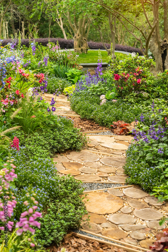 round wooden pathway winding in garden with flowers