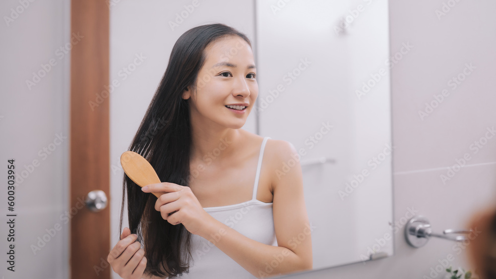 Happy attractive young woman combing wet hair with comb in bathroom after shower at home. Hair care and healthy hair Happy attractive young woman combing wet hair with comb in bathroom after shower at home. Hair care and healthy hair