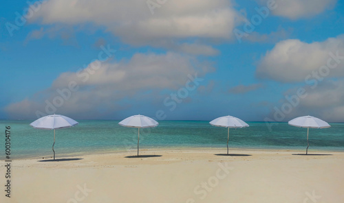 Summer tropical with white umbrella on the beach with  blue sky background