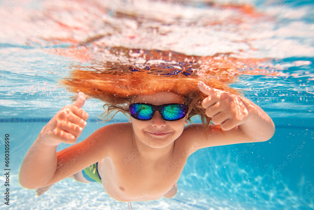 Child swimming underwater with thumbs up. Underwater kid swim under