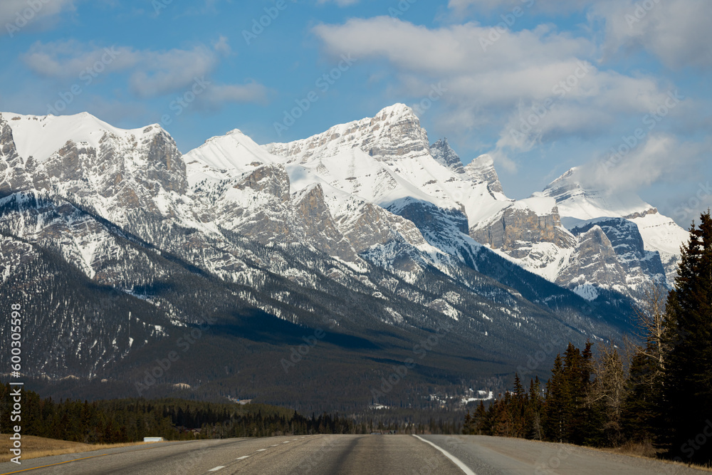 Magnificent scenery along the highway to Banff National Park in spring time with blue sky behind cascading snow capped mountains above. 