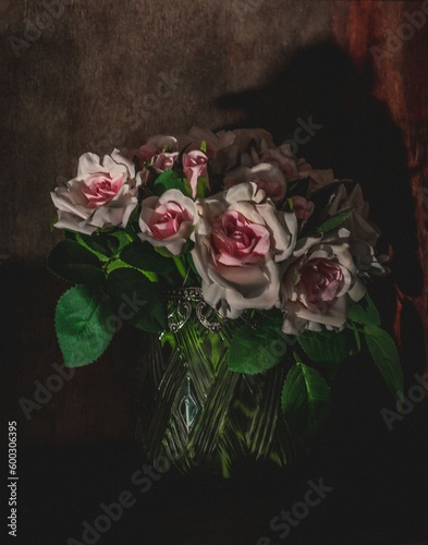 A spooky shadow of a bird hides behind a bouquet of roses on a shelf