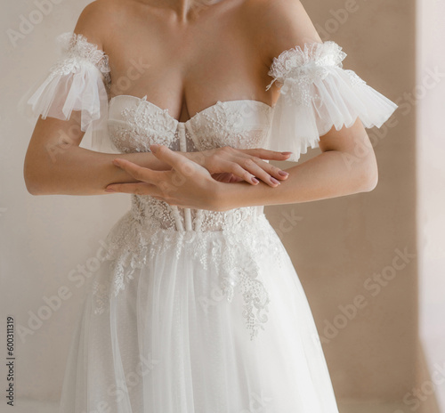 Trendy classic wedding dress with cleavage and wide short sleeves decorated with floral lace. Bride in the shoulderless white wedding dress with deep neckline and fancy sleeves